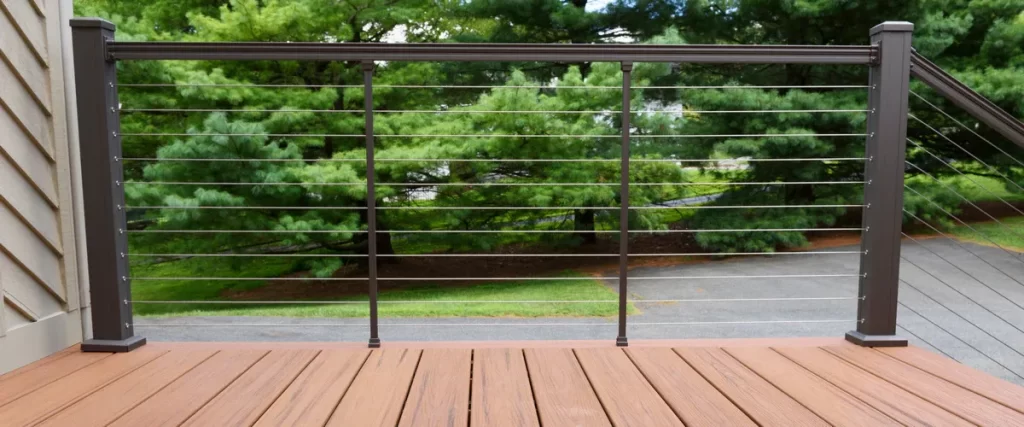 Wind-Resistant Deck Design for the Omaha–Lincoln Corridor A modern horizontal cable deck railing system with dark bronze posts offering an unobstructed view of a wooded backyard.
