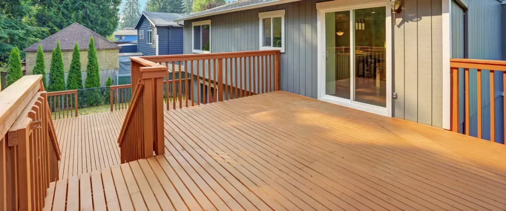 A view of a finished, warm-toned stained wooden deck showing the transition from a sliding glass door to the outdoor seating area and railings.