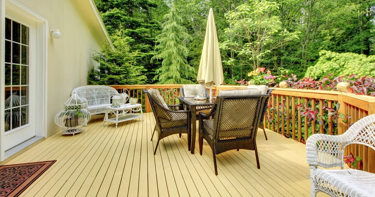 A high-end wooden deck with modern outdoor furniture and a scenic backyard view.
