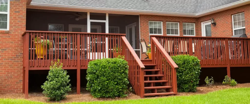 A completed modern multi-level deck featuring grey composite boards and sleek black metal railings with wide stairs.