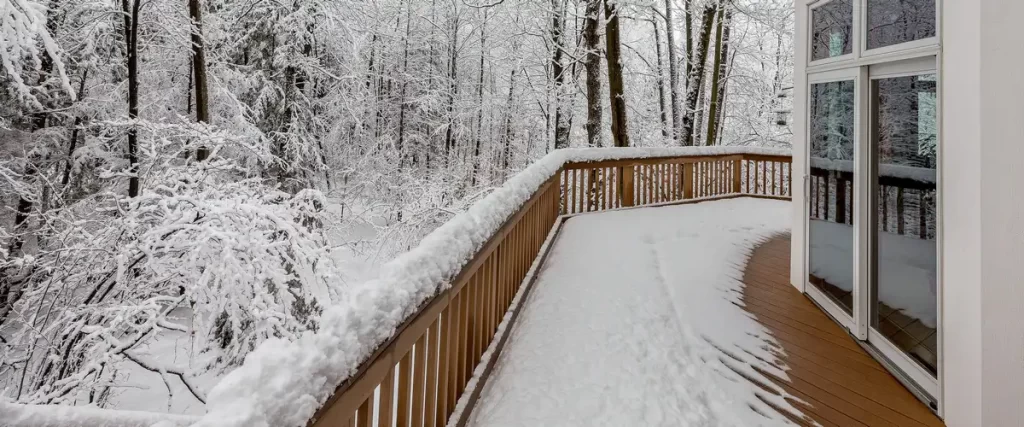 A backyard deck covered in white snow during the peak of winter season.