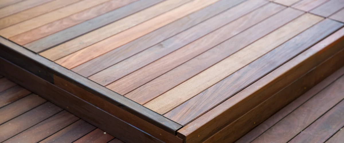 Close-up view of a newly finished multi-toned wooden deck surface showing the natural wood grain, plank alignment, and edge detailing.