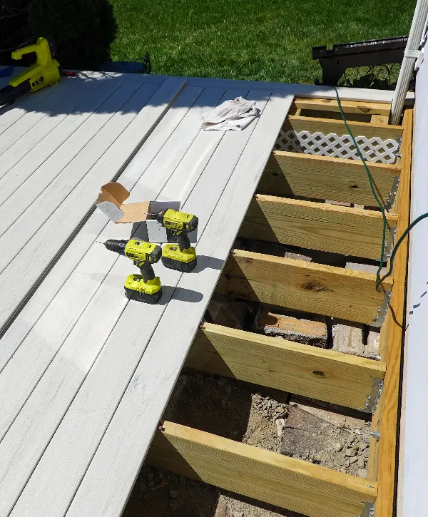 High-quality deck repair in Ralston, NE, showing the installation of new composite boards over exposed wooden support joists with power drills.